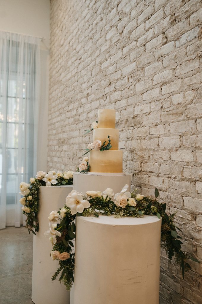 Three tier white cake at a wedding sitting on a ornate cake tables. 