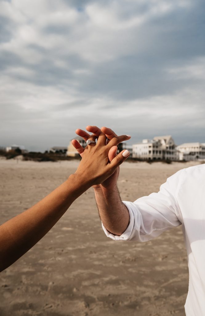 Man and woman holding hands, woman has a large diamond ring. Shot by Galveston wedding photographer, Brittany Emmanuel. 