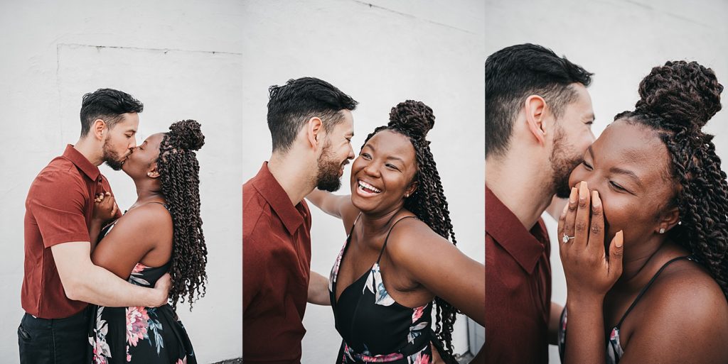 Man and woman kissing and laughing in front of a white wall by a Houston Engagement photographer. 