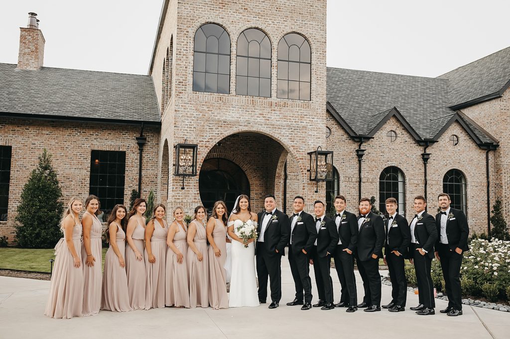 Large wedding party outside a brick building for an elegant & neutral Houston wedding. 