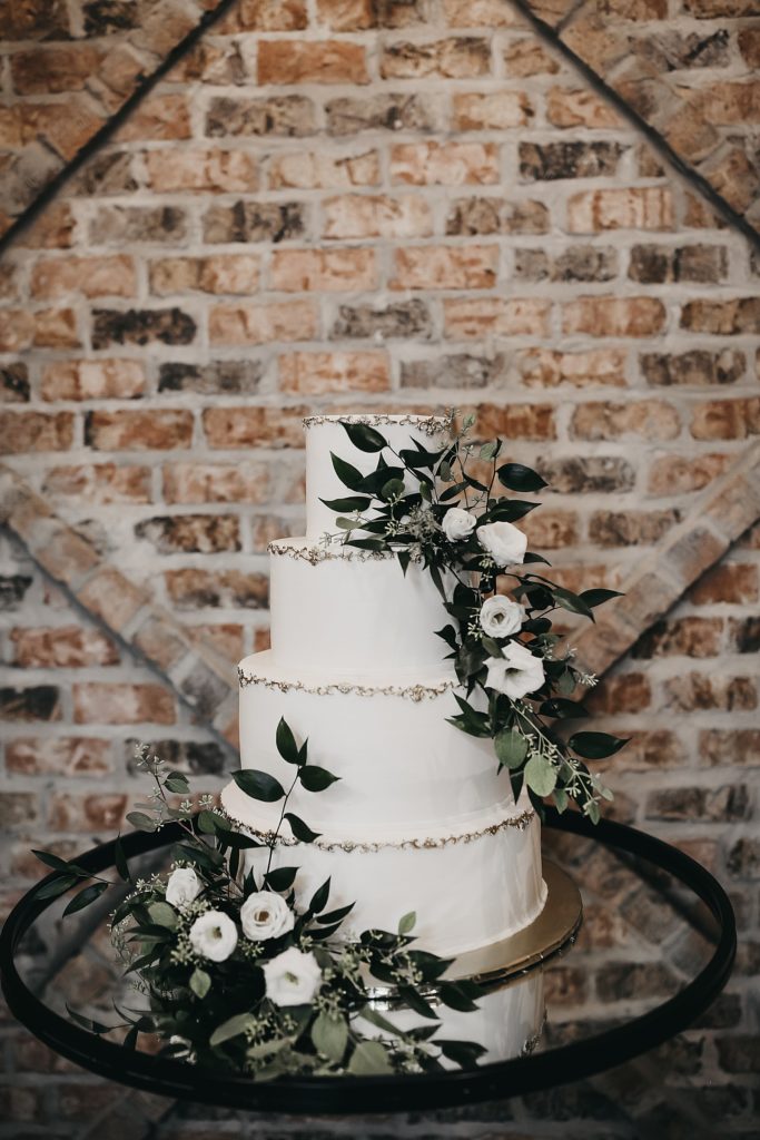 Four tier white cake with greenery and white roses by Texas photographer, Brittany Emanuel. 