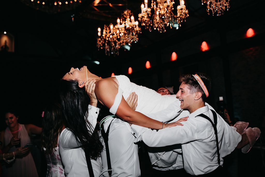 Bride being carried across the dance floor by groomsmen, by Houston wedding photographer Brittany Emanuel. 