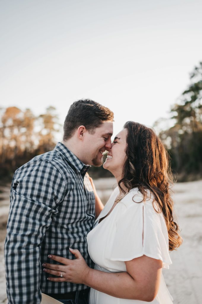 couple putting their heads together and leaning for a kiss at their engagement session 